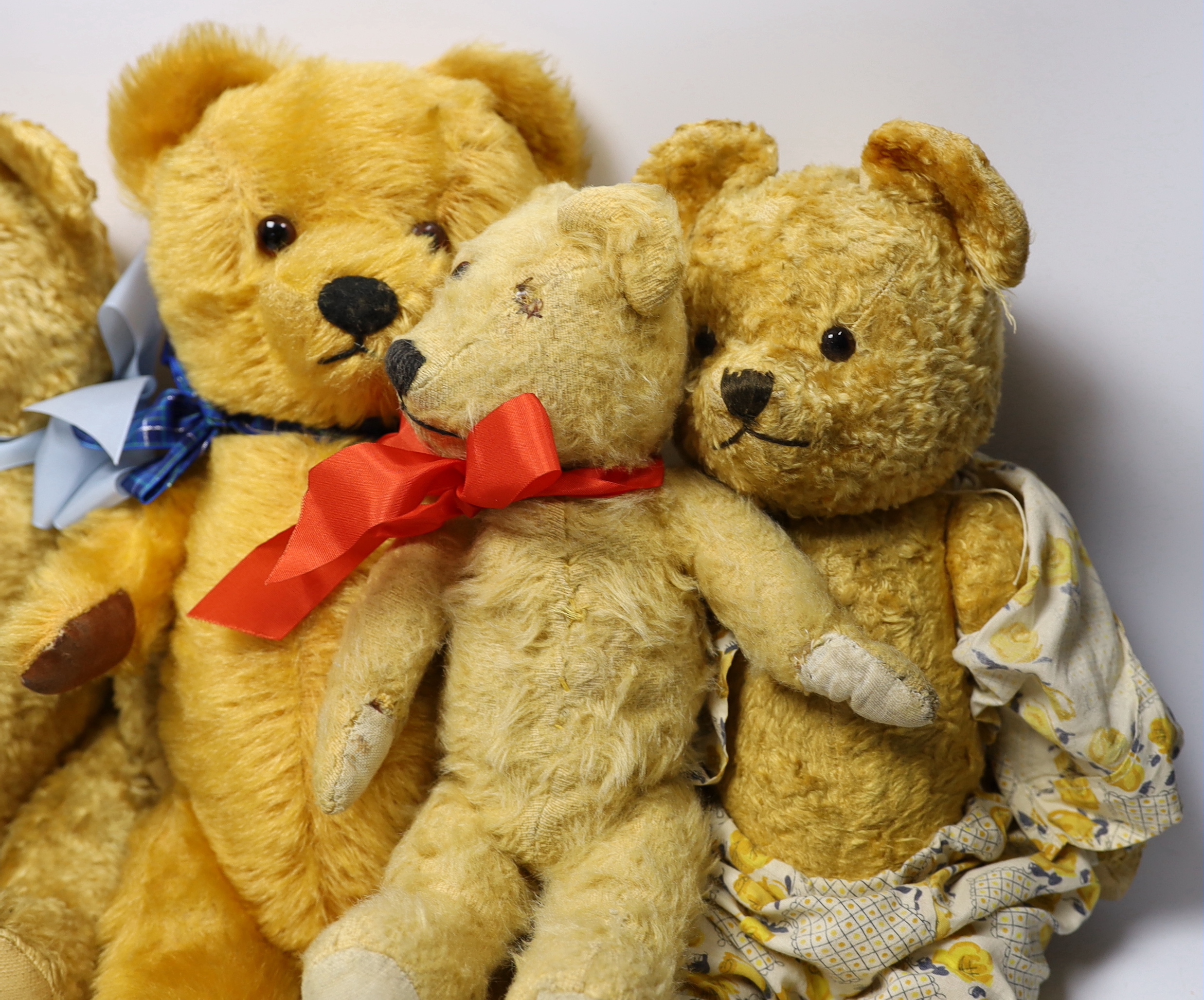 A golden plush bear with pale blue ribbon, 38cm, together with three others (4)